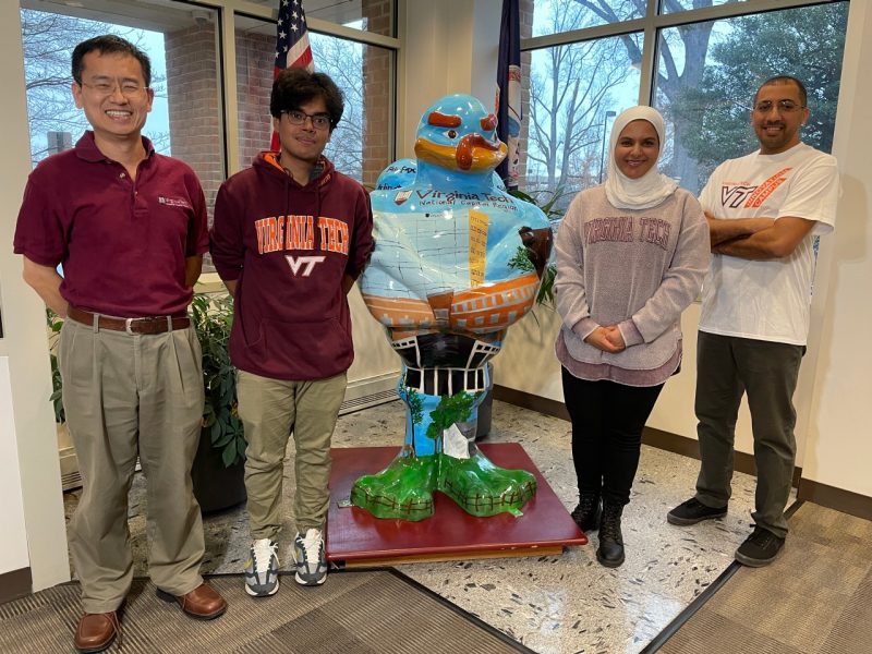 Professor and student research team standing with Hokie Bird Statue at the Northern Virginia Center in Falls Church