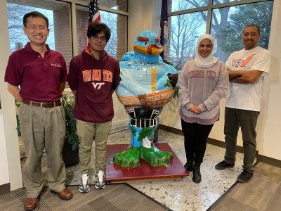 Professor and student research team standing with Hokie Bird Statue at the Northern Virginia Center in Falls Church