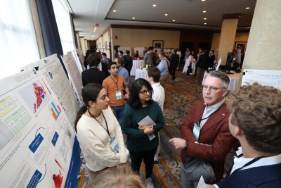 President Tim Sands (second from right) talks with a grounp of students at a poster session.